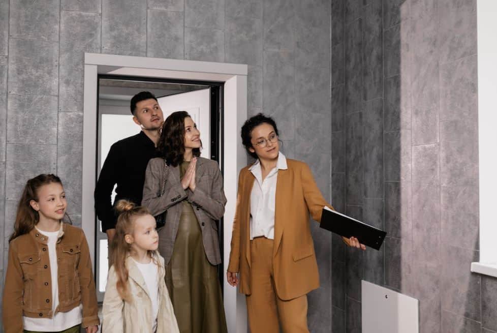 Famiglia accolta da una consulente all'ingresso di una casa