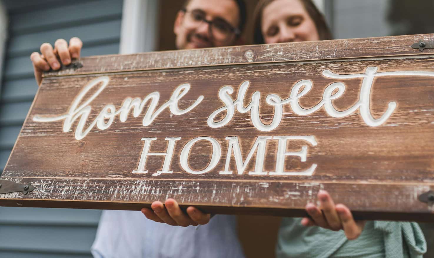 Coppia che regge un'insegna in legno Home sweet home