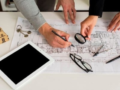 Professionisti che esaminano planimetrie catastali con una lente d'ingrandimento