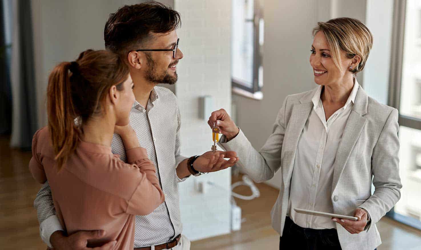 Consulente immobiliare che consegna le chiavi a una coppia